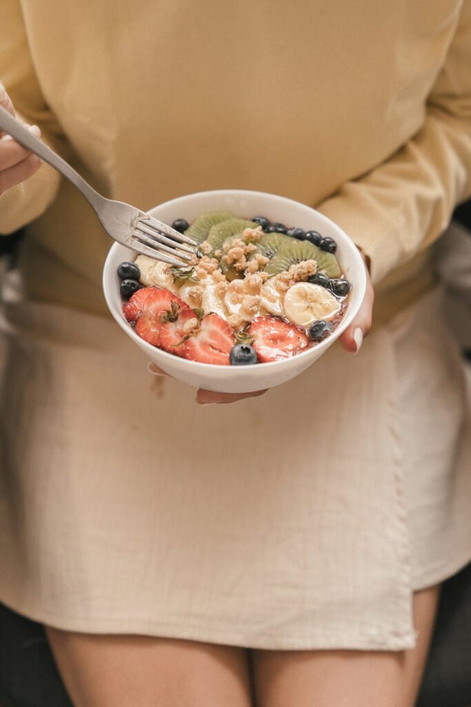 A white ceramic bowl overflowing with fresh, vibrant blueberries, raspberries, and strawberries.
