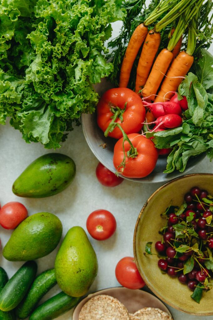 An overhead shot of a rustic wooden table covered in a vibrant assortment of whole foods including bell peppers, broccoli, and berries.