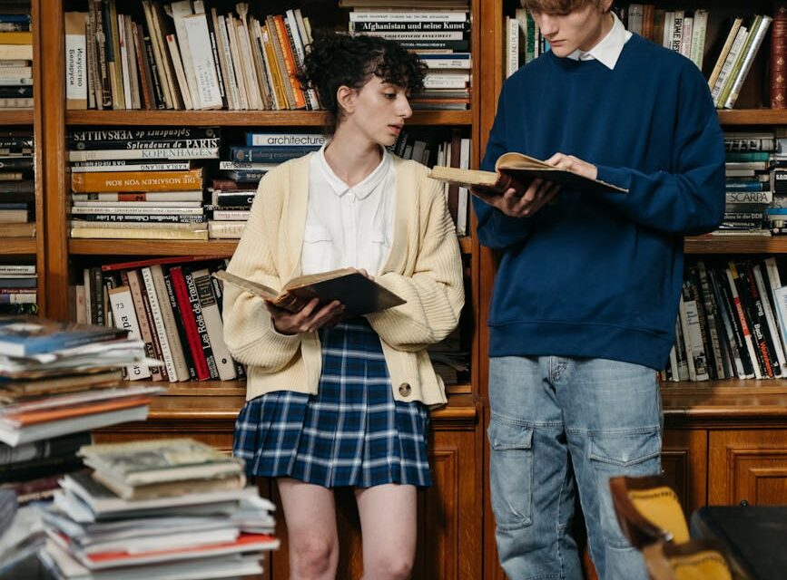 A diverse group of university students focused on their books and laptops in a sunlit library.