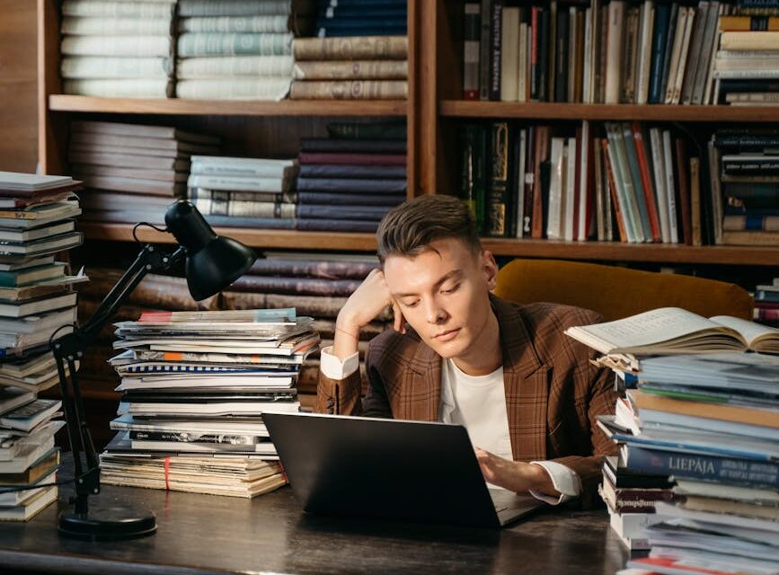 A young student with glasses focused on a book in a quiet, well-lit library.